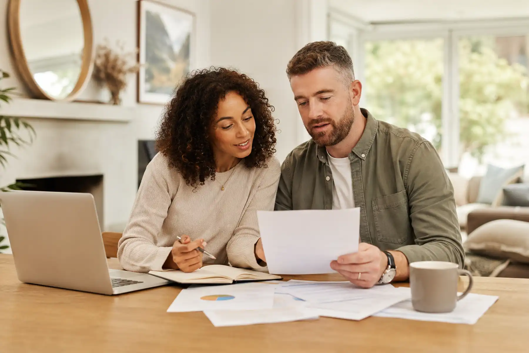A couple reviewing mortgage and protection information together with a laptop and notebook.