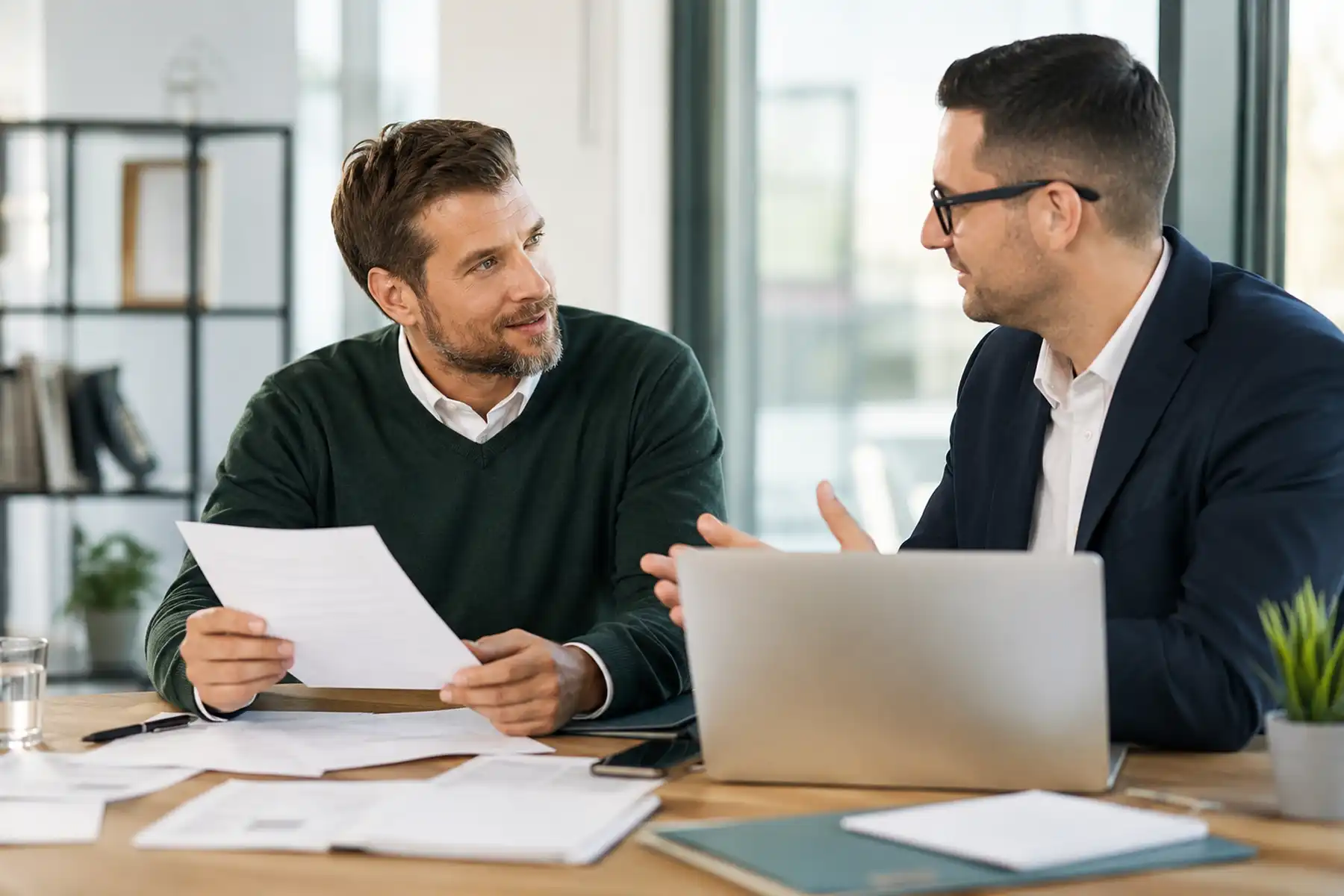 Mortgage adviser explaining contractor mortgage options to a contractor in a modern UK office.