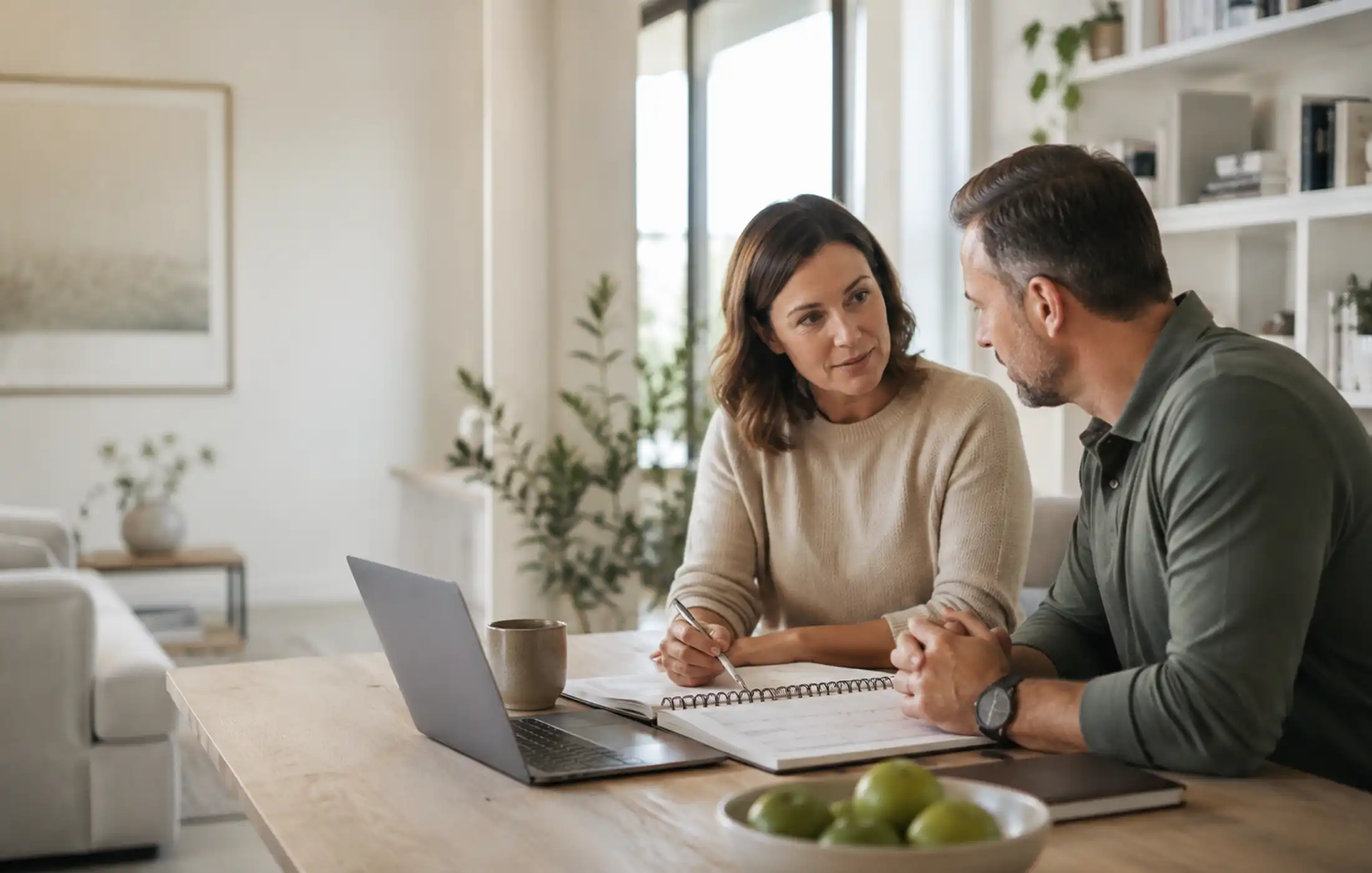 Recovering professional planning a phased return to work at home with a calendar and laptop while discussing policy waiting periods and claim limits with an adviser.