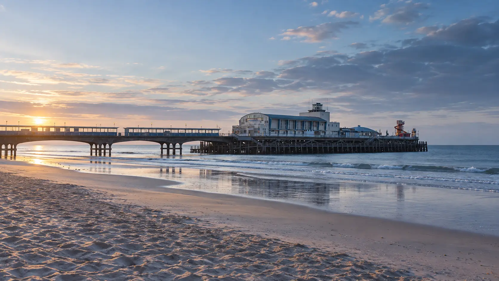 Bournemouth Pier and seafront viewed across the beach in early-morning light.